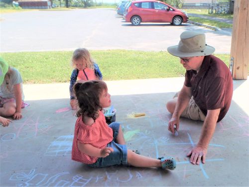 A Grandfather Joins in the Fun of Drawing on the Pavilion Floor